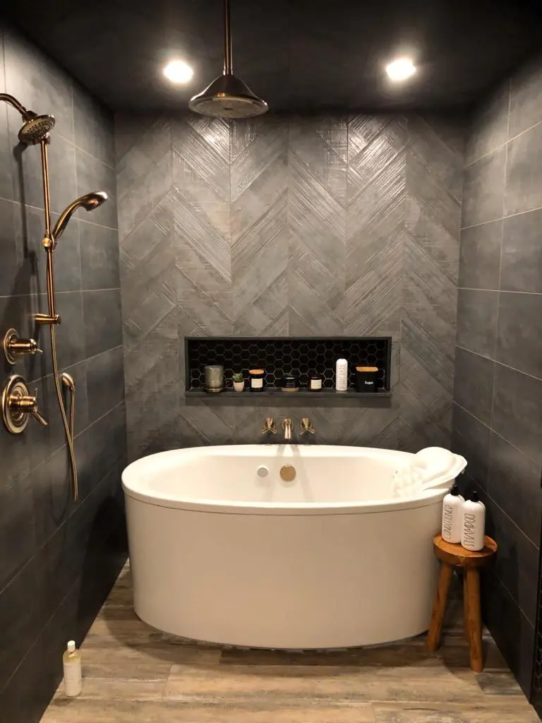 67b5180bd303e_IMG_0611 A bathroom with a tub, shower head and tiled walls.